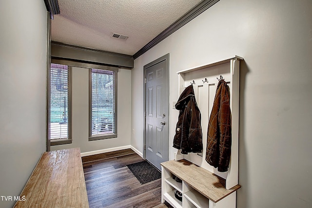 mudroom featuring visible vents, crown molding, baseboards, dark wood finished floors, and a textured ceiling