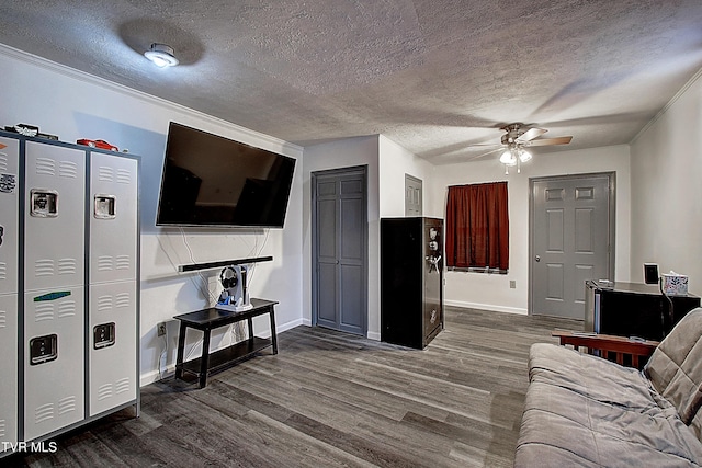 living area featuring dark wood-type flooring, ornamental molding, baseboards, and a textured ceiling