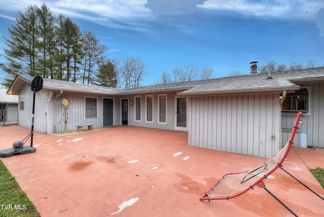 back of house featuring board and batten siding, a shingled roof, and a patio area