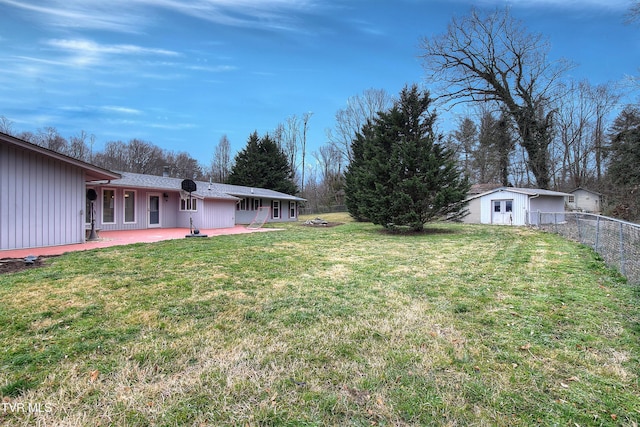 view of yard featuring a patio area, an outbuilding, and fence