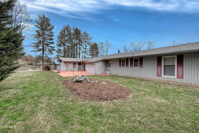 rear view of property featuring a patio, a lawn, and fence