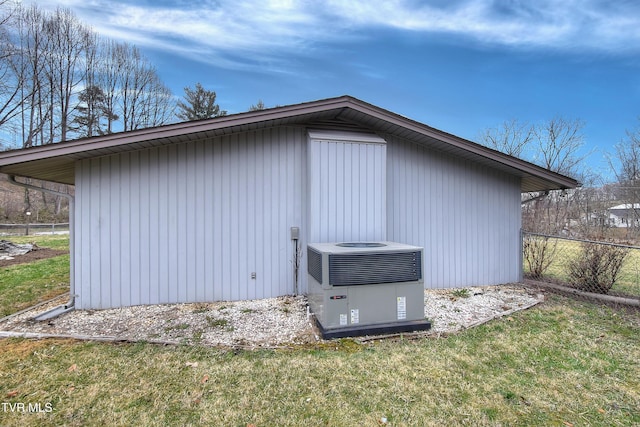 view of outbuilding with central AC unit, an outdoor structure, and fence