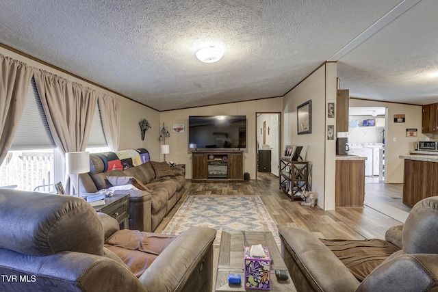 living area with ornamental molding, washer and dryer, a textured ceiling, and wood finished floors