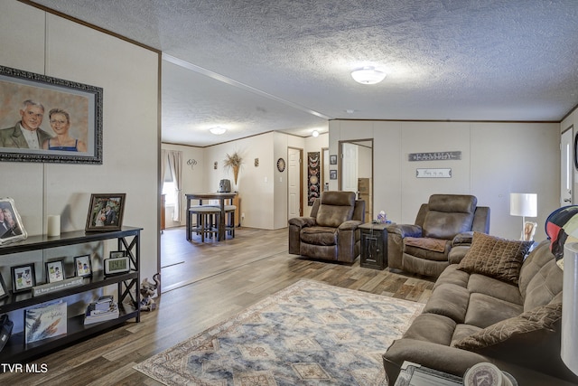 living area featuring a textured ceiling, wood finished floors, lofted ceiling, and crown molding