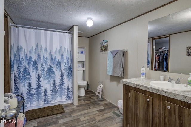 full bath with a textured ceiling, vanity, wood finished floors, and toilet