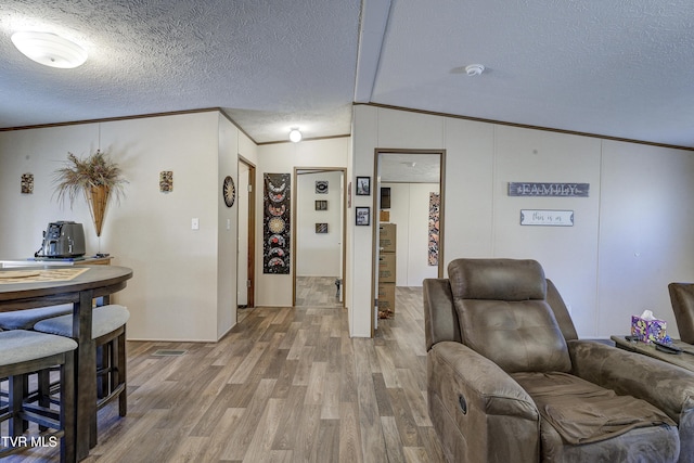 living room featuring lofted ceiling, a textured ceiling, crown molding, and wood finished floors