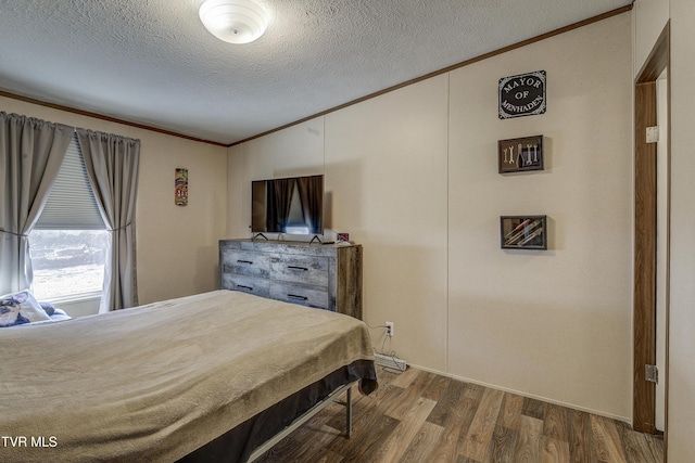 bedroom with crown molding, a textured ceiling, and wood finished floors