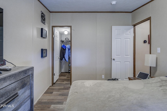 bedroom with dark wood-style floors, a spacious closet, ornamental molding, and a closet