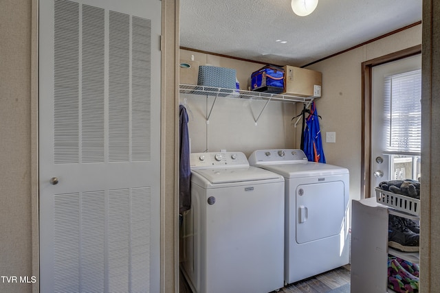 laundry room with crown molding, washing machine and clothes dryer, a heating unit, a textured ceiling, and laundry area