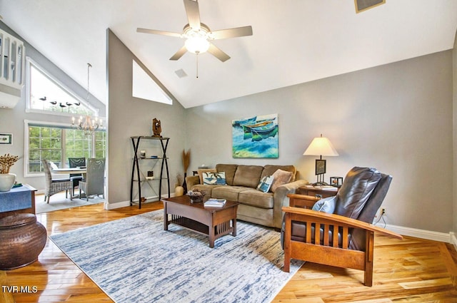 living room with ceiling fan with notable chandelier, high vaulted ceiling, wood finished floors, and baseboards