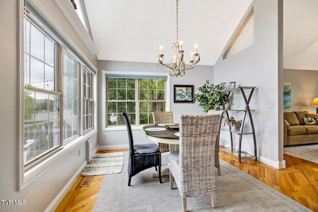 dining room featuring baseboards, visible vents, lofted ceiling, wood finished floors, and a chandelier