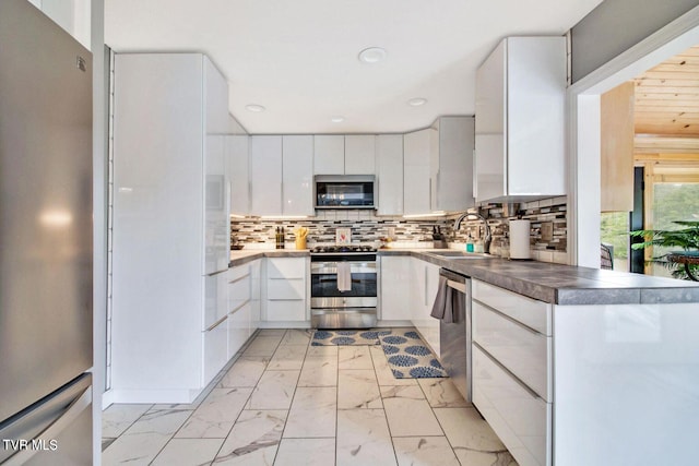 kitchen featuring white cabinets, modern cabinets, appliances with stainless steel finishes, marble finish floor, and a sink