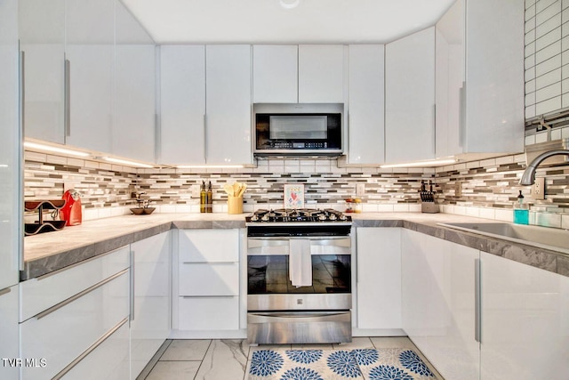 kitchen with stainless steel appliances, a sink, light countertops, and white cabinets