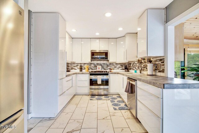 kitchen with marble finish floor, appliances with stainless steel finishes, white cabinets, a sink, and modern cabinets