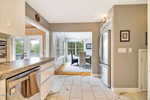 kitchen featuring marble finish floor, stainless steel fridge, baseboards, and french doors