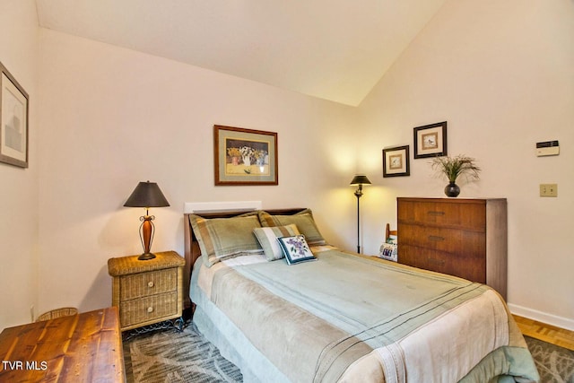 bedroom with lofted ceiling and baseboards