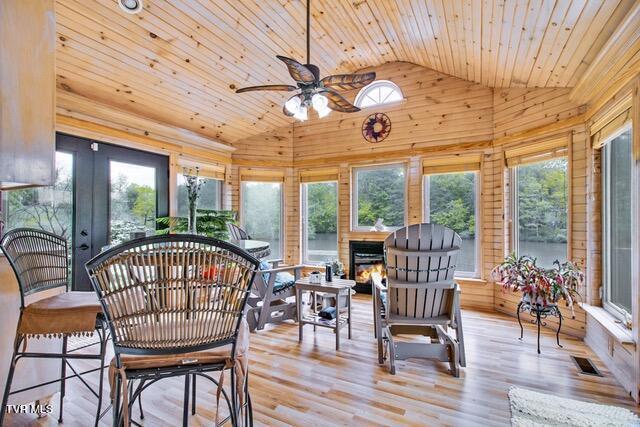 sunroom with a warm lit fireplace, wood ceiling, visible vents, and vaulted ceiling