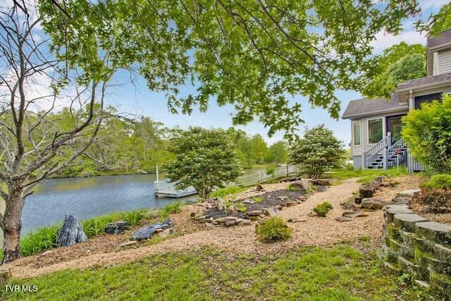 view of yard featuring a water view, a boat dock, and entry steps