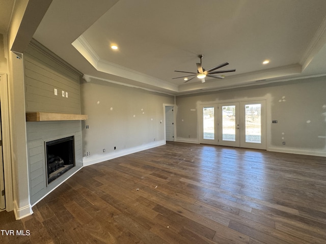 unfurnished living room featuring a large fireplace, dark wood-style flooring, and a raised ceiling