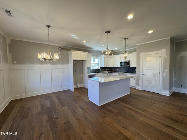 kitchen with visible vents, dark wood finished floors, stainless steel microwave, an inviting chandelier, and white cabinetry