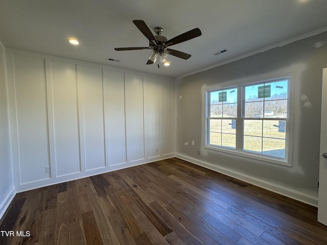 unfurnished room featuring dark wood-type flooring, visible vents, and a decorative wall