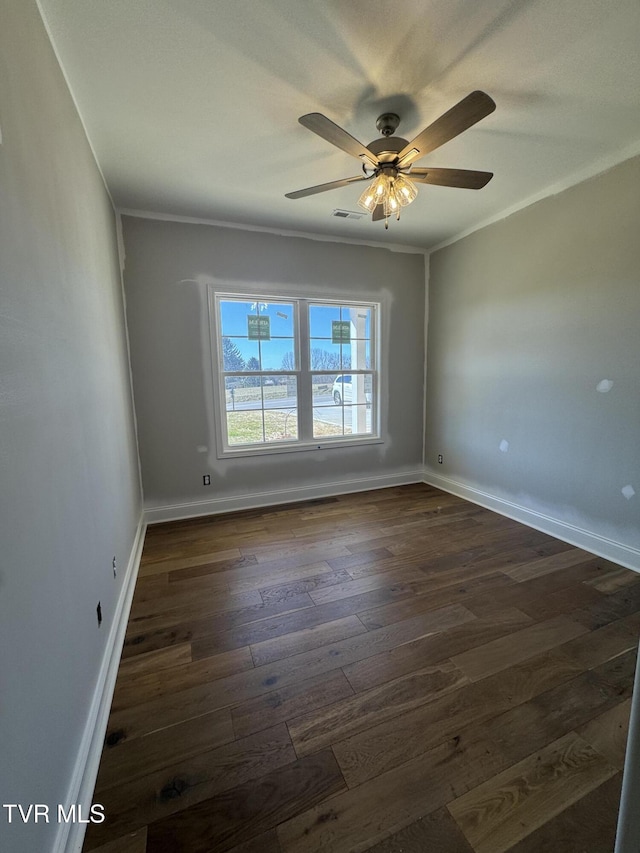 unfurnished room with dark wood-type flooring, a ceiling fan, visible vents, baseboards, and crown molding