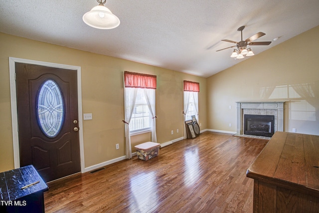 entrance foyer featuring visible vents, wood finished floors, vaulted ceiling, a textured ceiling, and a fireplace