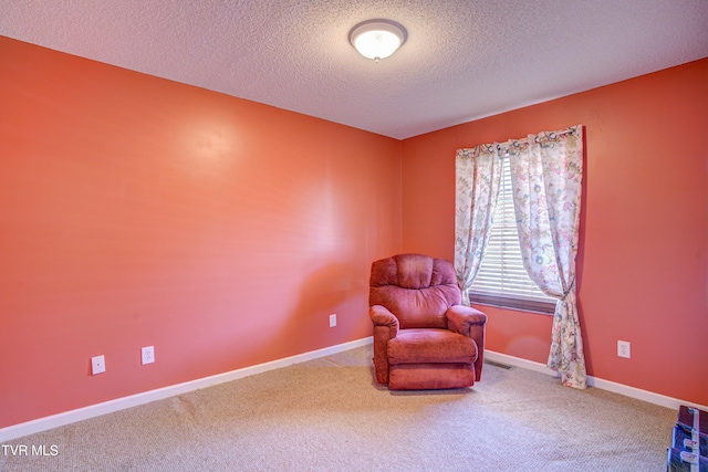 sitting room with carpet floors, visible vents, a textured ceiling, and baseboards