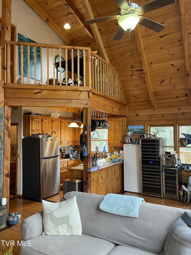 living area featuring beam ceiling, wooden ceiling, ceiling fan, and light wood finished floors