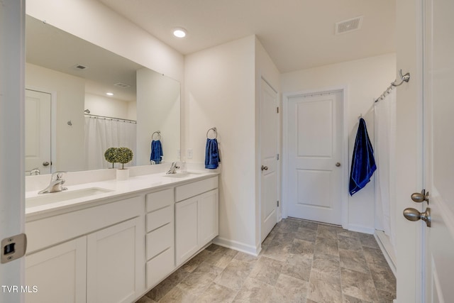 bathroom with visible vents, a sink, baseboards, and double vanity