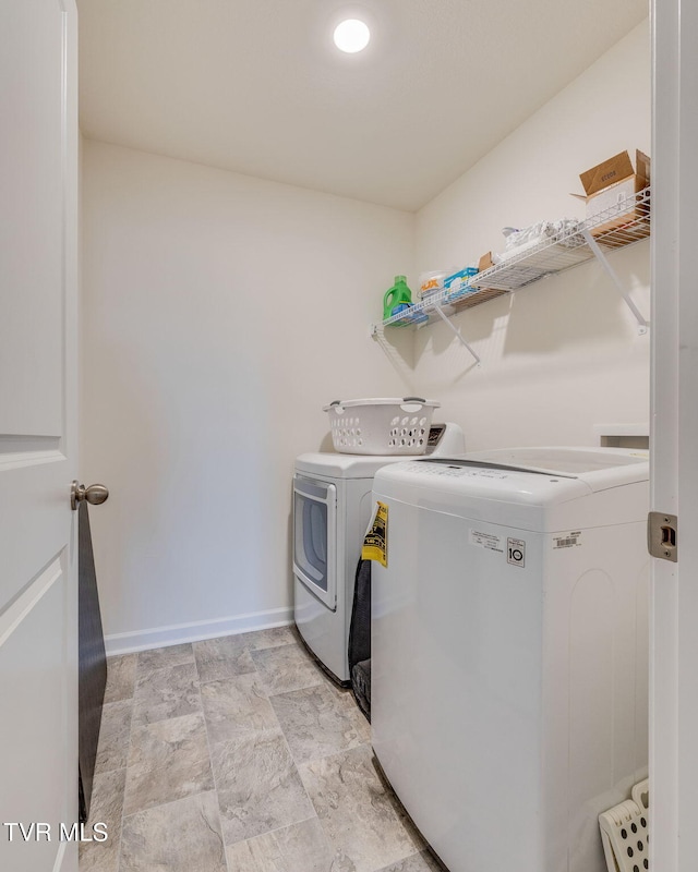 laundry area with laundry area, stone finish floor, independent washer and dryer, and baseboards