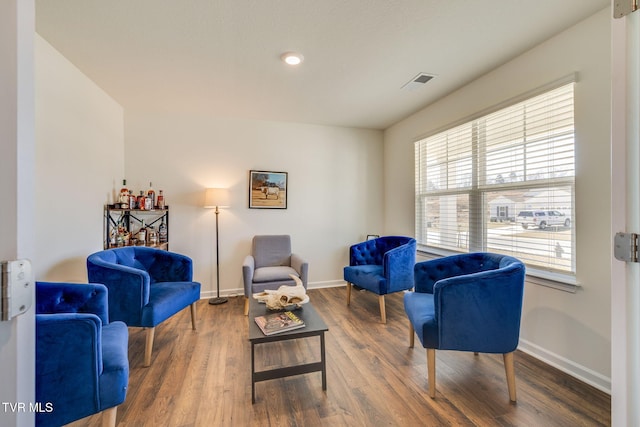 living area with baseboards, visible vents, and wood finished floors