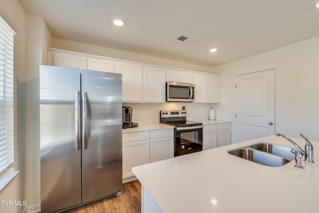 kitchen featuring stainless steel appliances, a sink, light countertops, and white cabinetry