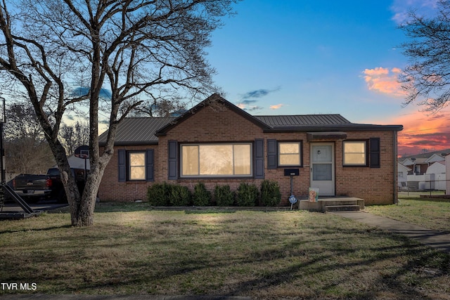 view of front facade with metal roof, brick siding, and a front yard