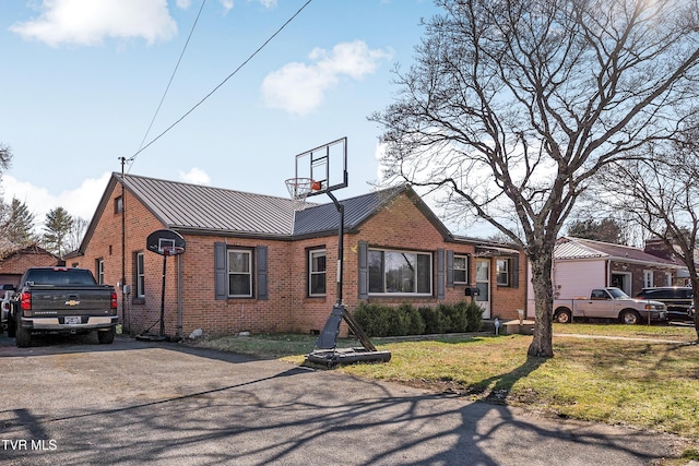 view of front of home featuring a standing seam roof, metal roof, a front lawn, and brick siding