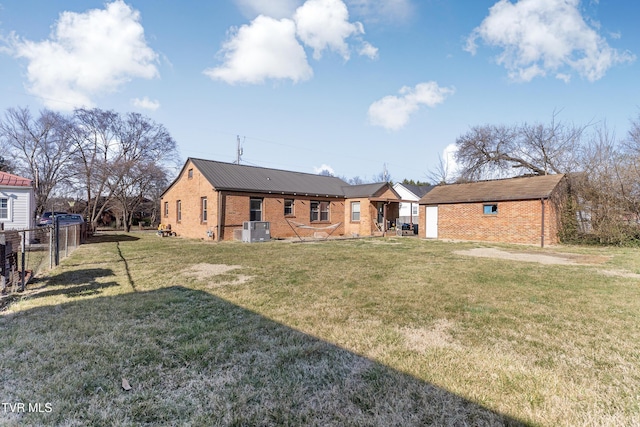 rear view of house featuring brick siding, fence, central AC, and a lawn