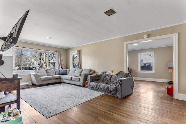 living area with baseboards, ornamental molding, and wood finished floors