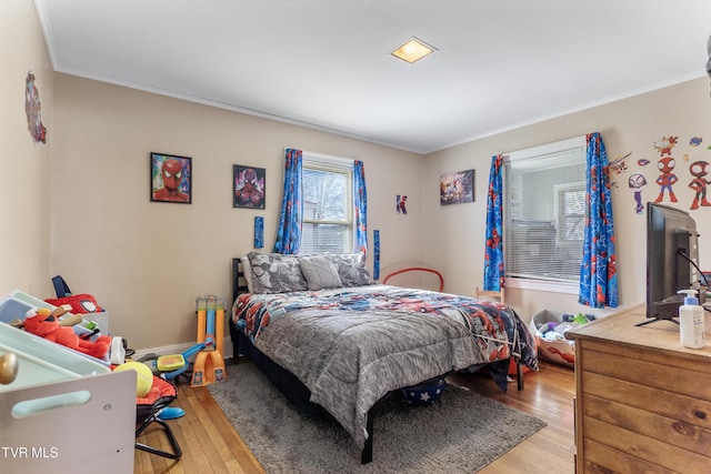 bedroom with light wood-type flooring, crown molding, and baseboards