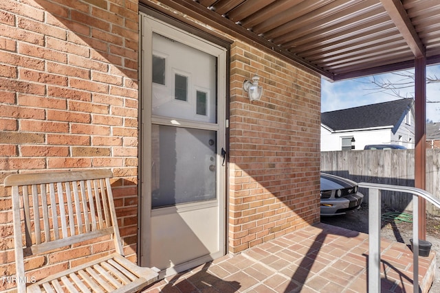 property entrance with fence and brick siding