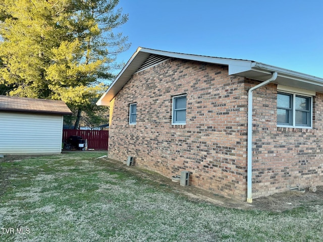 view of side of property with crawl space, brick siding, a yard, and fence