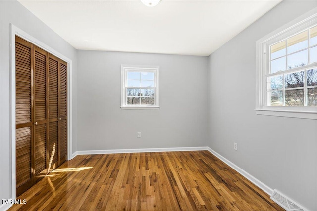 unfurnished bedroom with baseboards, visible vents, a closet, and wood finished floors