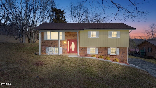 split foyer home with brick siding and a lawn