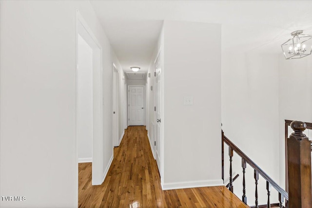 hall featuring baseboards, dark wood finished floors, and an upstairs landing