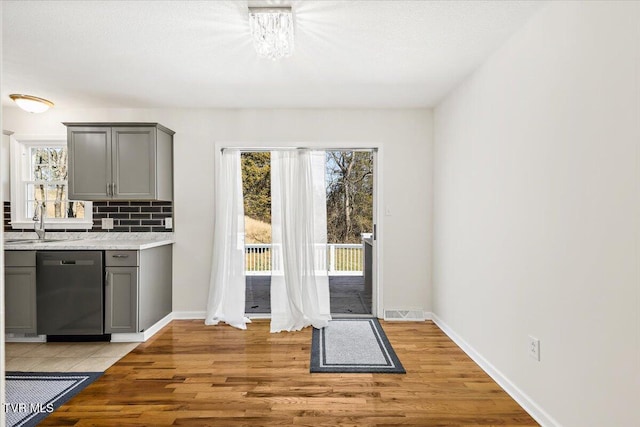 interior space featuring a sink, stainless steel dishwasher, backsplash, and gray cabinets