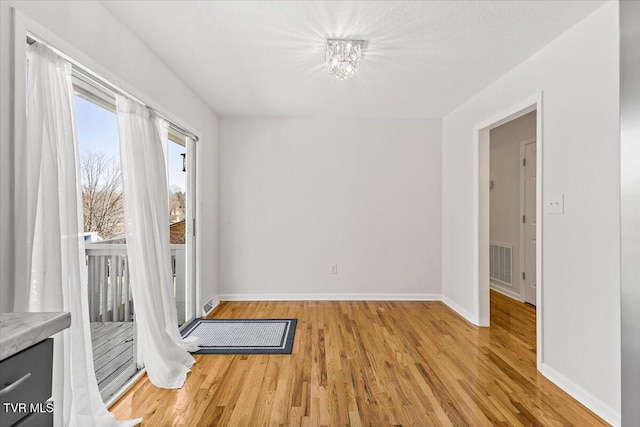 interior space featuring light wood-type flooring, visible vents, and baseboards