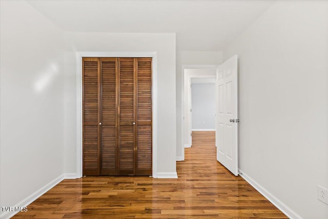 unfurnished bedroom with a closet, baseboards, and wood finished floors