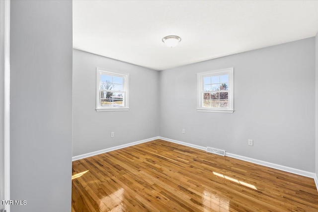 spare room with visible vents, baseboards, and wood finished floors