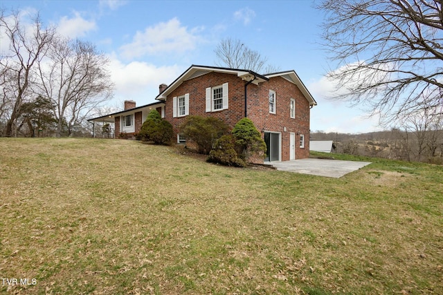 view of side of property with a chimney, brick siding, a garage, a patio area, and a lawn
