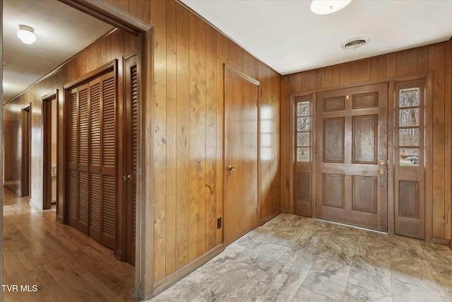 foyer entrance with visible vents and wood walls