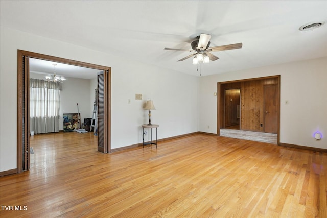 spare room featuring visible vents, baseboards, light wood finished floors, and ceiling fan with notable chandelier